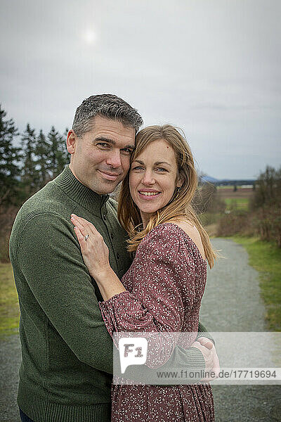 Mittleres erwachsenes Paar steht im Freien in einem Park in einer spielerischen  zärtlichen Umarmung; Aldergrove  British Columbia  Kanada