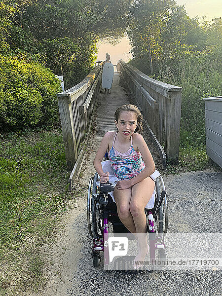 Mädchen mit kongenitaler Ullrich-Muskeldystrophie sitzt in ihrem Badeanzug in einem Rollstuhl auf einem Weg zum Strand nach einem Bad im Pamlico Sound; Nags Head  North Carolina  Vereinigte Staaten von Amerika