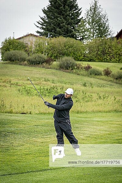 Amputee with one arm taking a swing on the golf course; Okotoks  Alberta  Canada