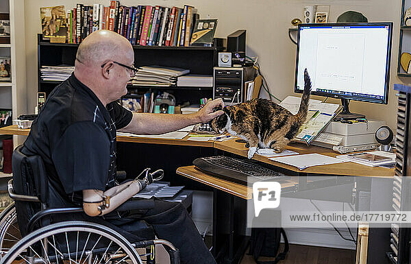 Mann mit doppelter Gliedmaßenamputation arbeitet von zu Hause aus am Computer; St. Albert  Alberta  Kanada