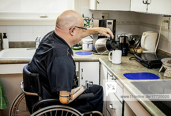 Mann mit doppelter Gliedmaßenamputation beim Einschenken von Kaffee in der Küche zu Hause; St. Albert  Alberta  Kanada
