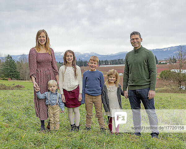 Outdoor portrait of a young family of six in a park with a view of the vast landscape in the background; Aldergrove  British Columbia  Canada