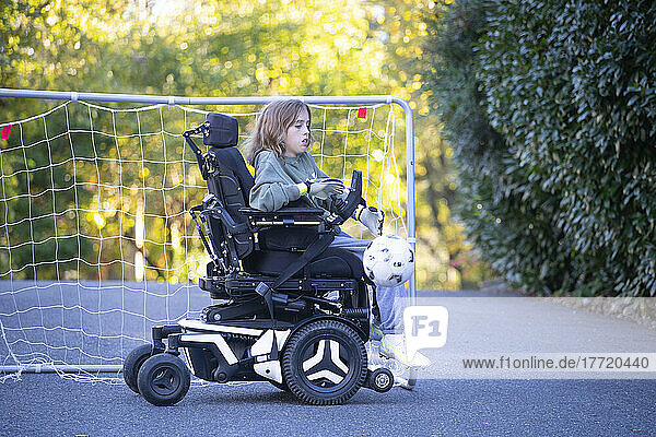 Elfjähriges Mädchen mit kongenitaler Ullrich-Muskeldystrophie spielt in ihrem Rollstuhl in der Nähe ihres Hauses Fußball; Cabin John  Maryland  Vereinigte Staaten von Amerika