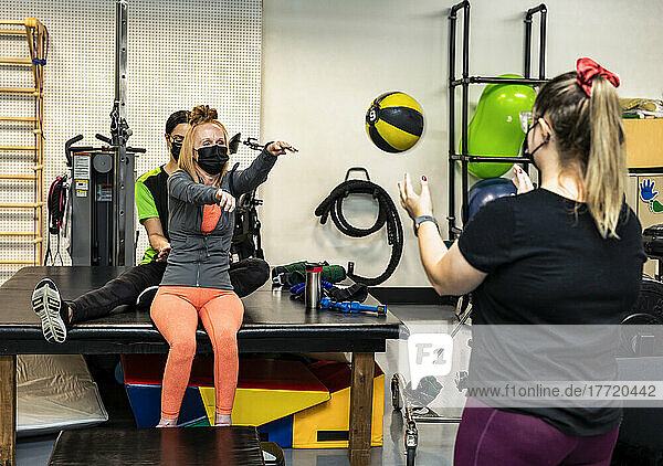 A paraplegic woman doing medicine ball tosses during her workout with her trainers: Edmonton  Alberta  Canada