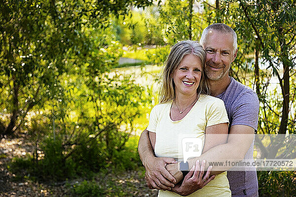 Outdoor portrait of a mature married couple standing posed in a park; Edmonton  Alberta  Canada