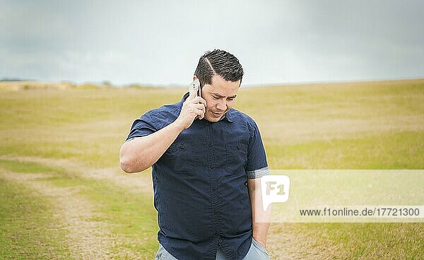 Man calling on the phone in the field  man on a road talking on the phone  person with his cell phone in the field calling on the phone  young person talking on the phone in a field