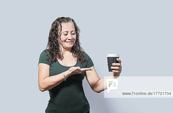 Lächelnde Person mit Kaffee auf isoliertem Hintergrund  Frau zeigt auf Einwegbecher mit Kaffee auf isoliertem Hintergrund  Eine Frau zeigt mit Blick auf Einwegbecher mit Kaffee