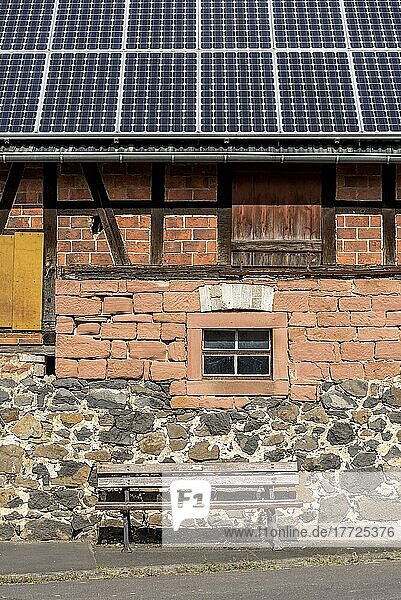 Historisches Bauernhaus mit Photovoltaikanlage  Solarpanele auf dem Dach  Hauswand mit unterschiedlich gestückeltem Mauerwerk aus Ziegelstein  Sandstein  Feldstein und Fachwerk  davor Sitzbank  Nidda  Hessen  Deutschland  Europa