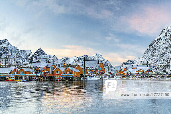 Fishermen's wood cabins covered with snow at sunset in the tiny village of Sakrisoy  Reine  Nordland  Lofoten Islands  Norway  Scandinavia  Europe
