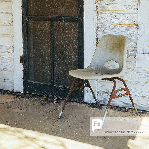 Chair on the porch by a door of old building.