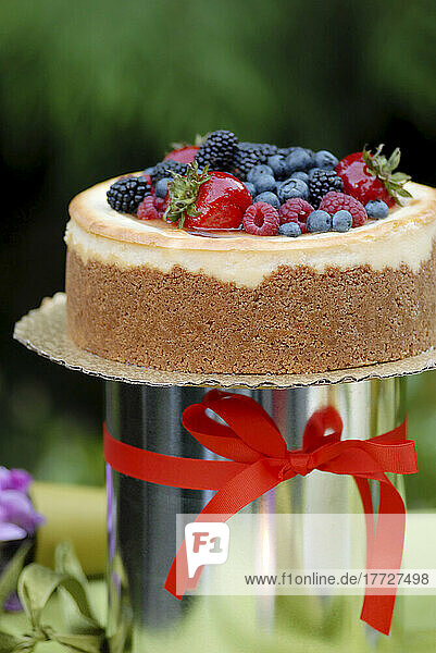 Ein Kuchen mit Zuckerguss und frischen Beeren und einer roten Schleife.