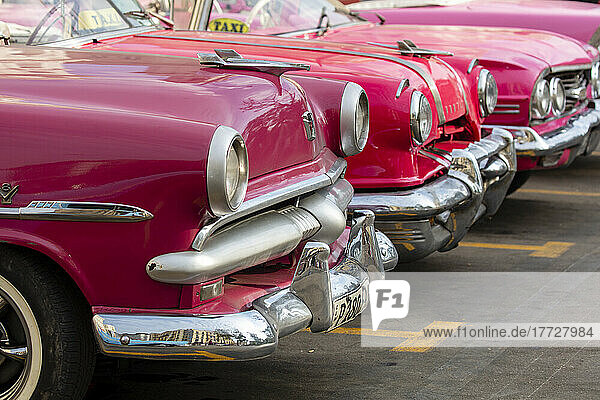 Red and pink vintage American car taxis on street in Havana  Cuba  West Indies  Central America