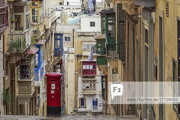Typical street scene of alley with traditional homes  colorful balconies and red post box  Valletta  Malta  Europe