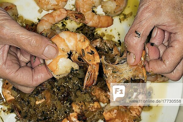 Food photography  woman's hands removing the shells of fried prawns