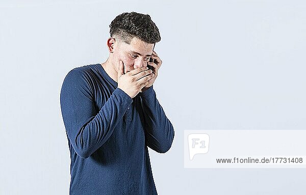 Man secretly talking on the phone  on an isolated background. Man talking on the phone covering his mouth  young man secretly talking on the phone  man on a confidential call