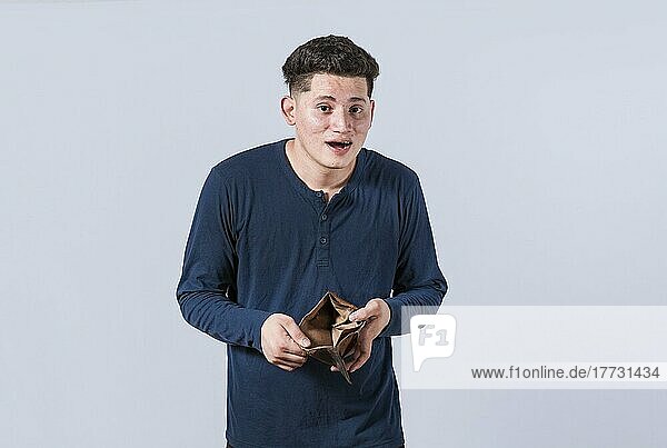 Unglücklicher und überraschter Mann schaut in eine leere Brieftasche  Mann sieht seine leere Brieftasche  junger Mann mit Brieftasche ohne Geld