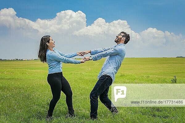 Glückliches Paar  das sich im Kreis auf dem Feld dreht  glückliches junges Paar  das sich auf dem Feld dreht und spielt  junges Paar  das sich auf dem Feld dreht