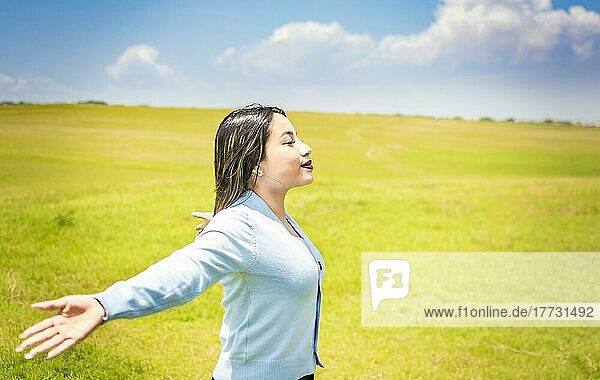 Glückliche Frau atmet frische Luft auf dem Feld und breitet die Arme aus  junge Frau lächelt und breitet ihre Hände auf der grünen Wiese aus  Konzept der Frau atmet frische Luft auf dem Feld