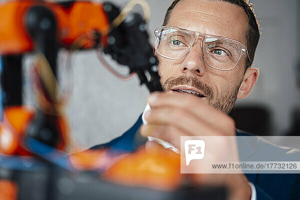 Engineer wearing eyeglasses looking at robotic model