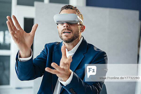 Businessman gesturing wearing virtual reality headset in office