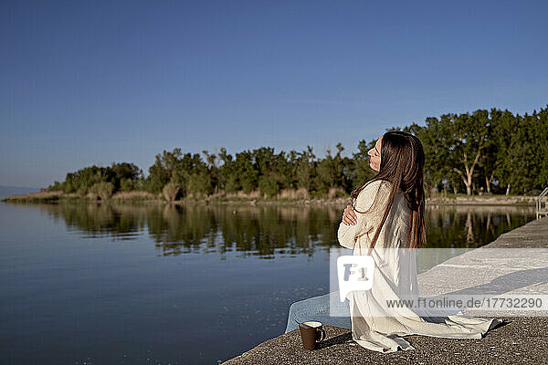 Frau umarmt sich auf dem Steg am See