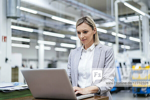 Businesswoman using laptop in factory