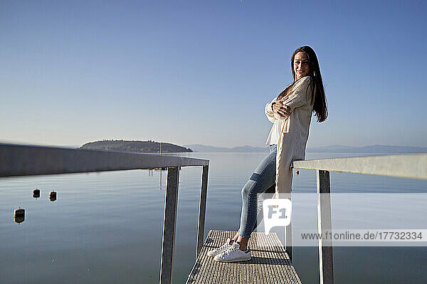 Lächelnde Frau steht auf Steg am See