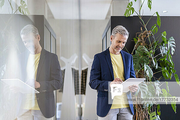 Mature businessman using digital tablet in office