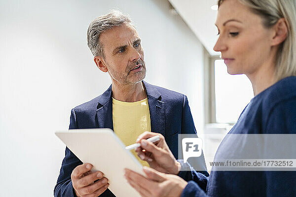 Businessman talking to businesswoman with digital tablet in office