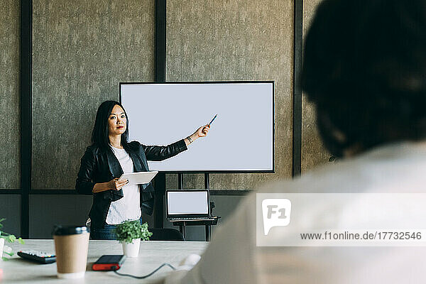 Mature businesswoman giving presentation to colleague at office