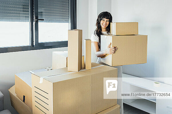 Smiling woman with cardboard boxes at new home
