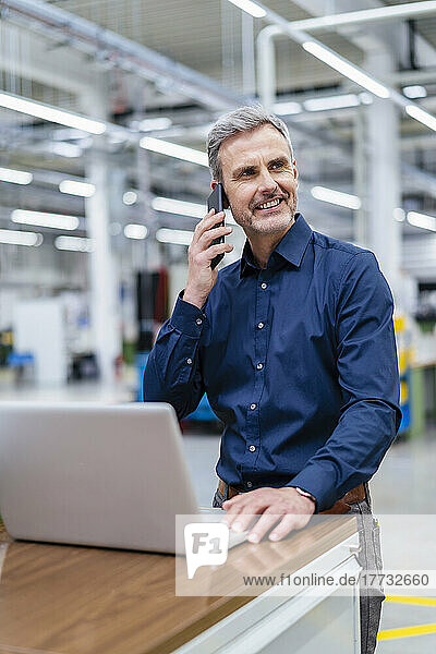 Mature businessman on the phone in factory