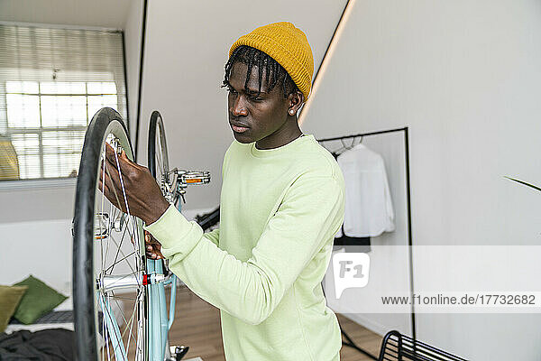 Young man repairing wheel of bicycle at home