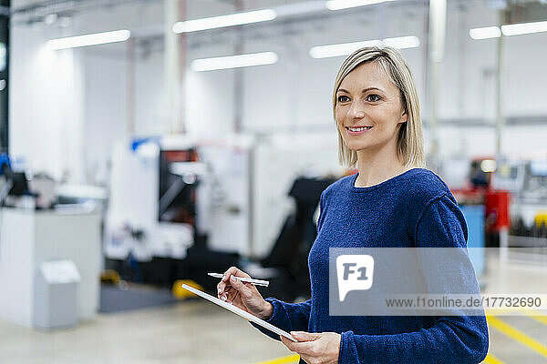 Businesswoman holding digital tablet in factory