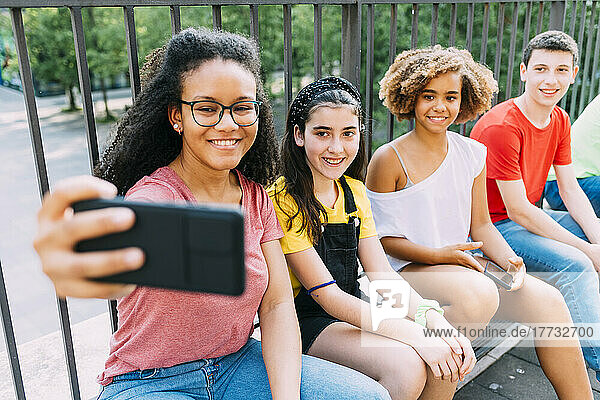 Glückliche junge Frau  die per Smartphone ein Selfie mit Freunden macht