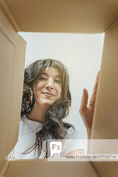 Smiling woman seen through cardboard box