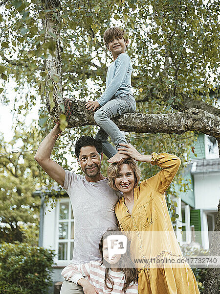 Happy family with boy sitting on tree in back yard