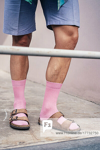 Beine eines Mannes mit rosa Socken und Sandalen