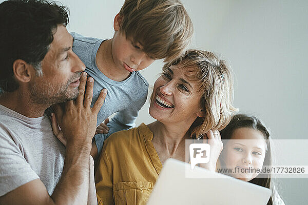 Happy woman looking at son by man and daughter at home