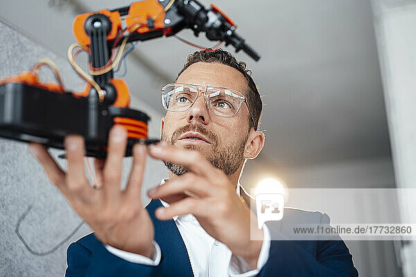Mature technician wearing eyeglasses testing robotic model