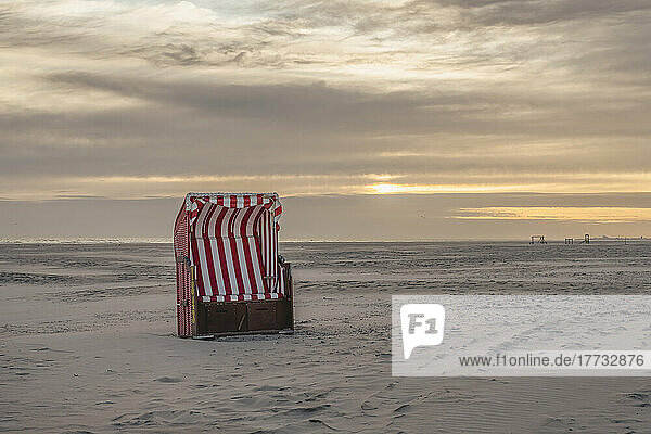 Germany  Lower Saxony  Juist  Hooded beach chair on empty beach at sunset