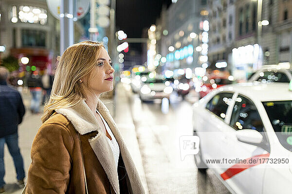 Thoughtful woman in city at night