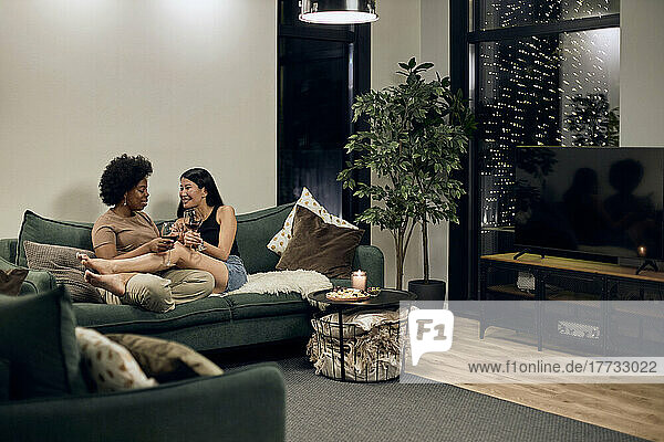 Glückliches schwules Paar  das zu Hause auf dem Sofa im Wohnzimmer sitzt und miteinander redet