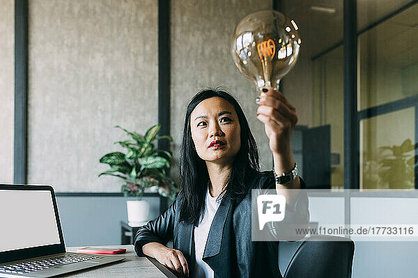 Businesswoman analyzing light bulb at office