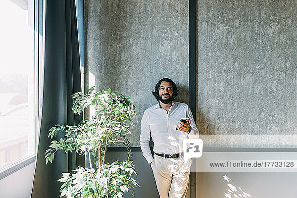 Businessman with smart phone in front of wall