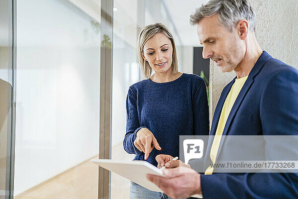 Geschäftsmann und Geschäftsfrau arbeiten gemeinsam an einem digitalen Tablet im Büro