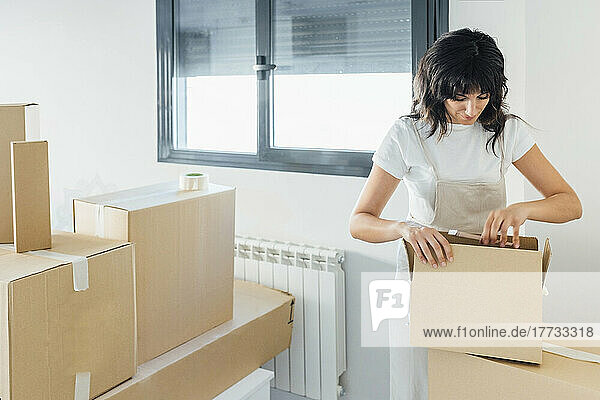 Woman unpacking cardboard box at new home