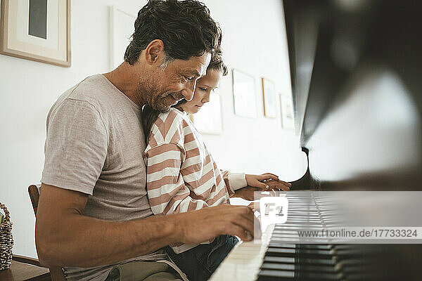 Happy father teaching piano to daughter at home