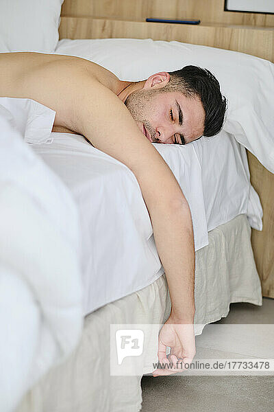 Shirtless young man sleeping in bed at home