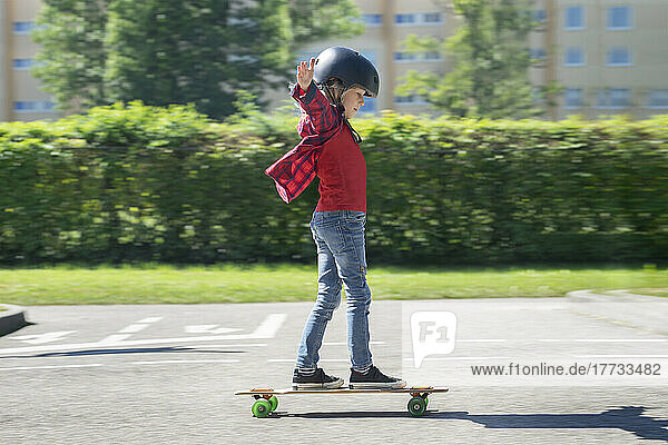Boy with arms outstretched skateboarding on traffic course
